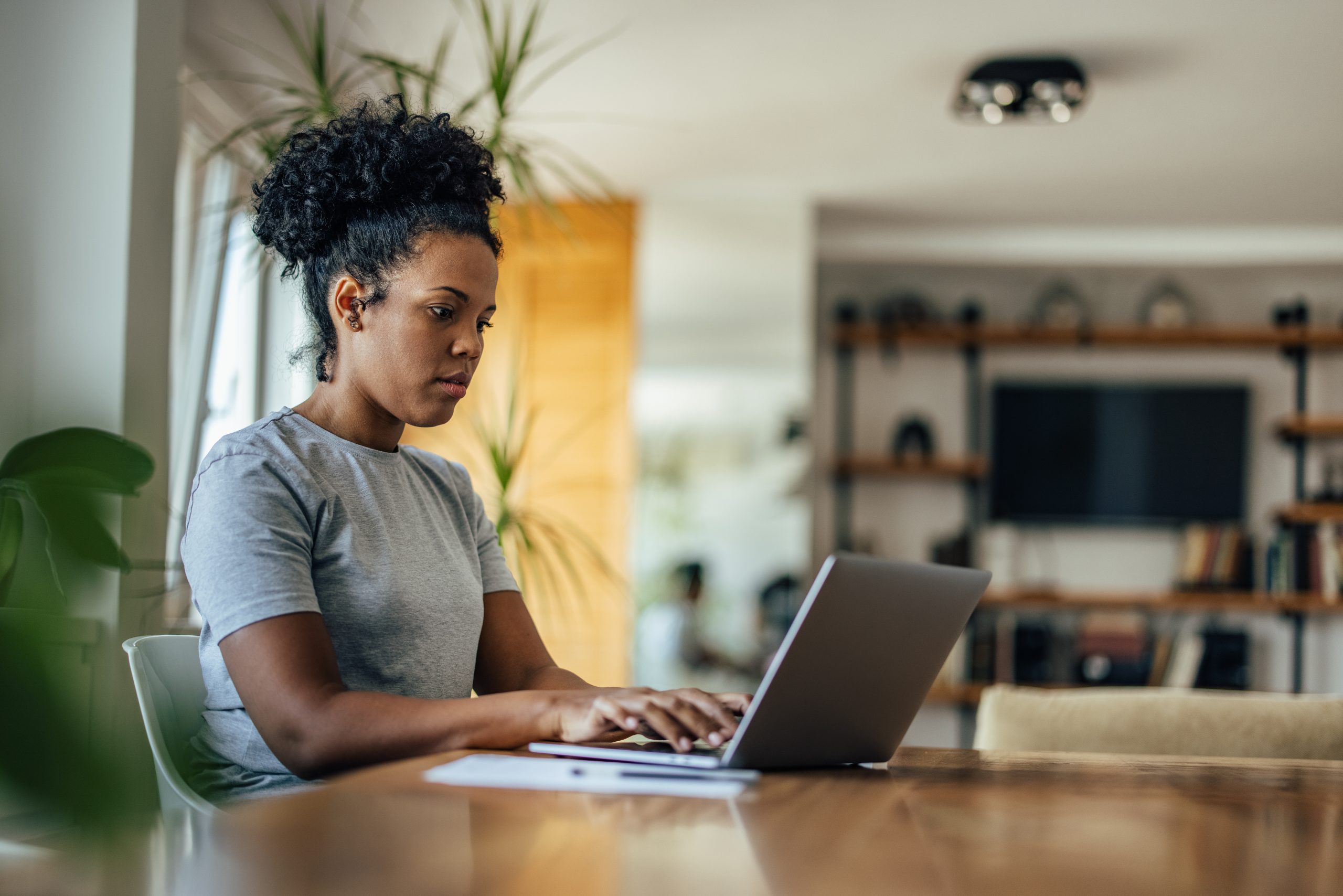 Young woman working on laptop in kitchen at home