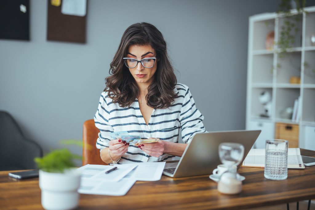 A busy black-haired business woman calculates expenses on a calc