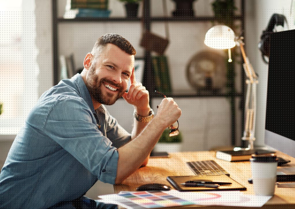 Young bearded man smiling at desk in home office