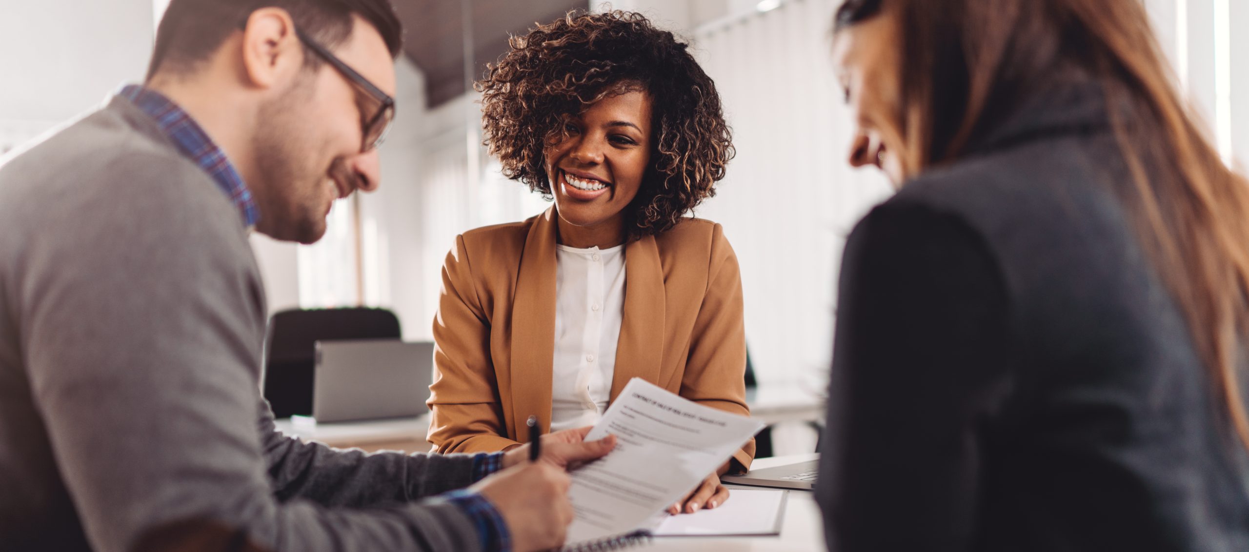 Couple sitting at the desk in the bank and signing loan agreement